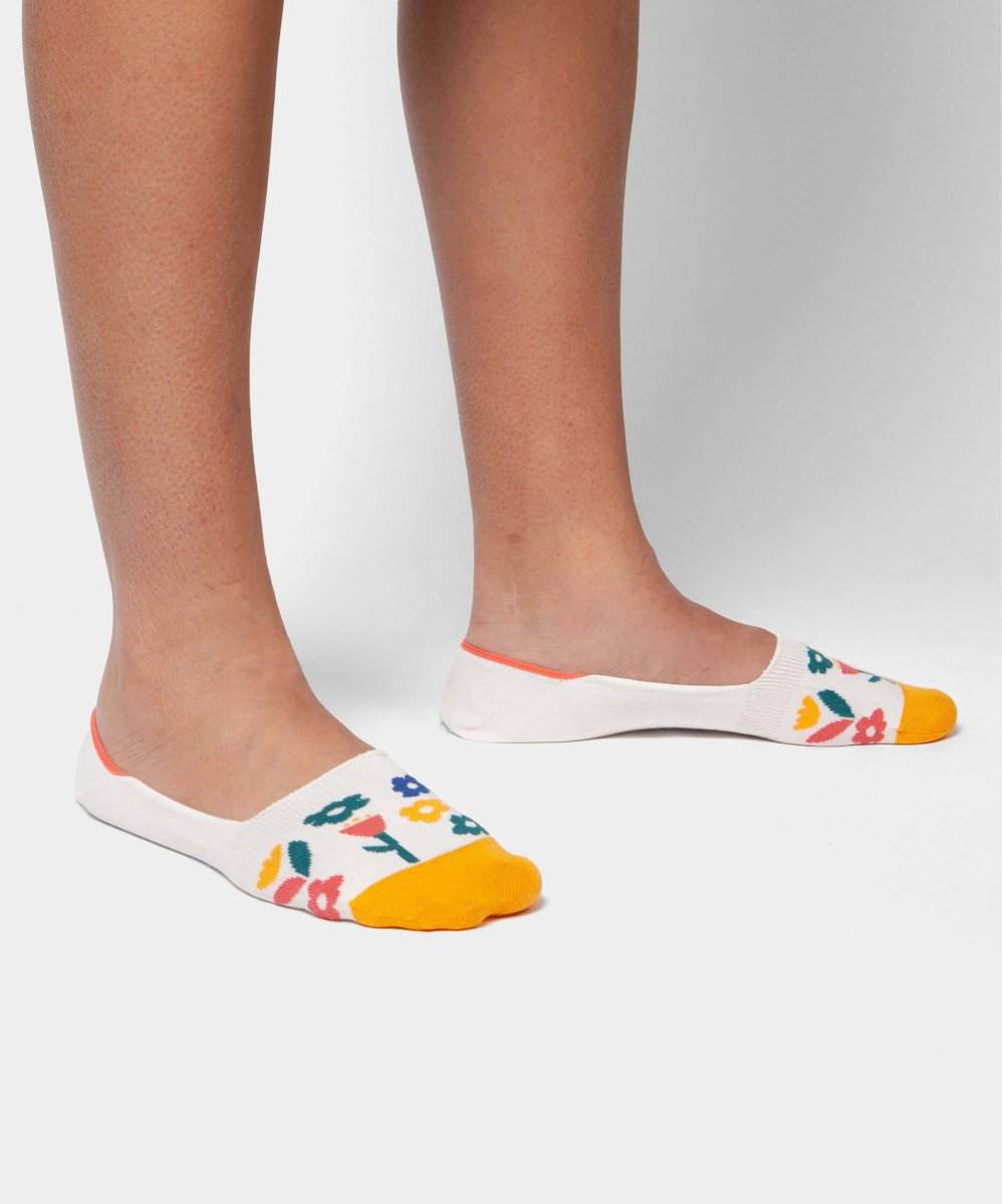 Weiße Socken mit Hidden White Meadow Design auf grünem Hintergrund