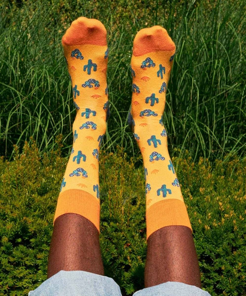 Tequila Sunrise Cocktail mit Sonnenaufgang in Mexiko und nackten Füßen in Socken